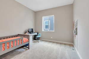 Carpeted bedroom with visible vents, a crib, and baseboards