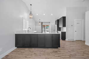 Kitchen with dark cabinets, light countertops, visible vents, and a peninsula