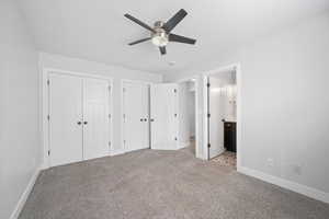 Unfurnished bedroom with multiple closets, light colored carpet, a ceiling fan, ensuite bath, and baseboards