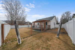 Back of house with a fenced backyard, a lawn, and a deck