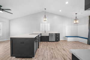 Kitchen featuring appliances with stainless steel finishes, light countertops, hanging light fixtures, and dark cabinetry