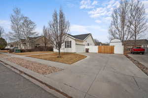 View of front facade featuring an attached garage, fence, driveway, a gate, and a residential view