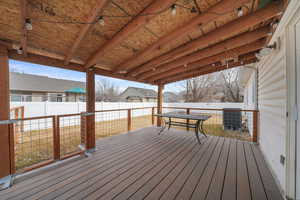 Wooden deck with outdoor dining space, cooling unit, and a fenced backyard