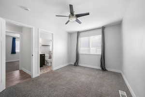 Unfurnished bedroom featuring visible vents, ensuite bathroom, a ceiling fan, carpet flooring, and baseboards