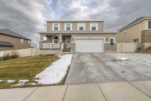 View of front of property with stucco siding, a porch, fence, driveway, and a front lawn