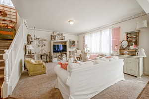 Living area featuring a textured ceiling, stairway, light carpet, and crown molding