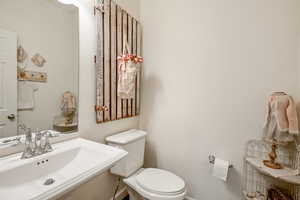 Half bath featuring baseboards, a sink, and toilet