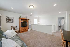 Living area with light carpet, baseboards, and recessed lighting