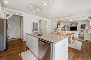 Kitchen featuring stainless steel appliances, open floor plan, white cabinetry, a sink, and an island with sink