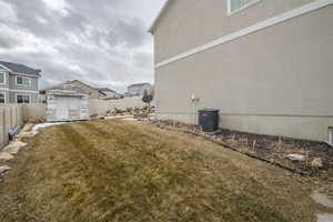 View of yard featuring a fenced backyard, an outbuilding, central AC, and a shed