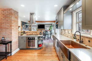 Kitchen featuring light wood-style floors, light countertops, island exhaust hood, and a sink