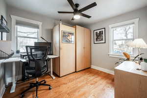 Office with light wood-type flooring, a wealth of natural light, baseboards, and a ceiling fan