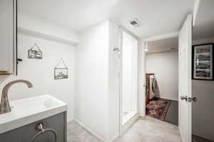 Bathroom featuring separate washer and dryer, vanity, visible vents, baseboards, and a shower stall