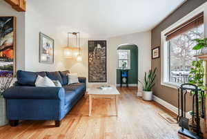 Living area featuring a wealth of natural light, arched walkways, baseboards, and light wood finished floors