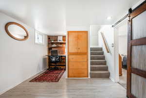 Office area featuring light wood-style floors, baseboards, and a barn door