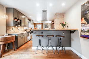 Kitchen with a breakfast bar, pendant lighting, light countertops, appliances with stainless steel finishes, and a peninsula