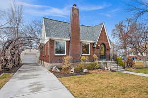 English style home with an outbuilding, roof with shingles, a chimney, a garage, and driveway