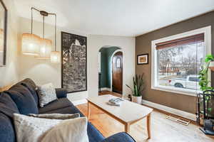 Living room featuring light wood-type flooring, visible vents, arched walkways, and baseboards