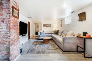 Living area featuring brick wall, wood finished floors, visible vents, and baseboards