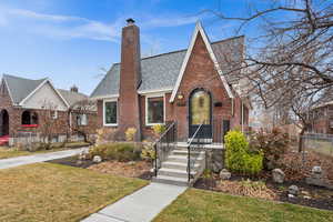 English style home featuring a front yard, brick siding, a chimney, and roof with shingles