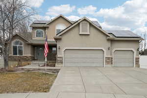 Traditional-style home with a garage, stone siding, and stucco siding