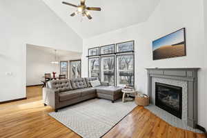 Living area featuring light wood-style floors, a fireplace, high vaulted ceiling, and baseboards