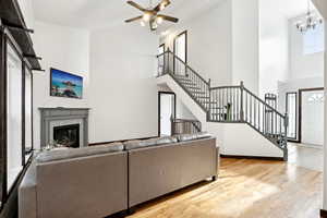 Living room featuring light wood-style flooring, stairs, a high ceiling, and a glass covered fireplace