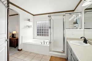 Full bathroom featuring tile patterned floors, crown molding, vanity, a shower stall, and a bath