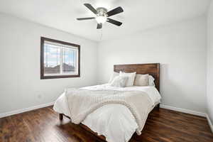 Bedroom with dark wood finished floors, baseboards, and ceiling fan