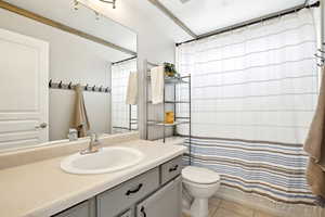 Full bath featuring toilet, a shower with shower curtain, vanity, and tile patterned floors