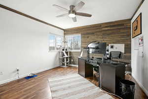 Office with a ceiling fan, dark wood-style flooring, wooden walls, and baseboards