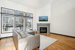 Living area featuring baseboards, light wood-style flooring, and a tiled fireplace