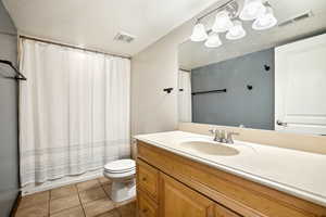 Full bathroom with toilet, shower / tub combo, tile patterned flooring, and visible vents