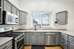 Kitchen with appliances with stainless steel finishes, a sink, and gray cabinetry