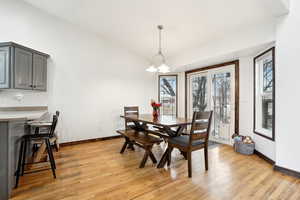 Dining space featuring light wood-type flooring, vaulted ceiling, and baseboards