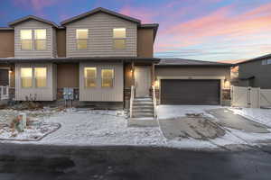 View of front of home with a garage, driveway, and a gate