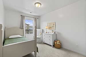 Bedroom featuring light carpet, baseboards, visible vents, and a textured ceiling