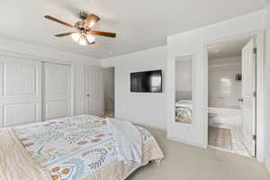 Bedroom with a closet, light colored carpet, a ceiling fan, connected bathroom, and baseboards