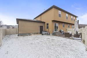 Snow covered property featuring cooling unit, a fenced backyard, a gate, and stucco siding