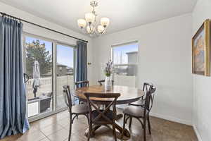 Dining space featuring baseboards, an inviting chandelier, tile patterned floors, and a healthy amount of sunlight