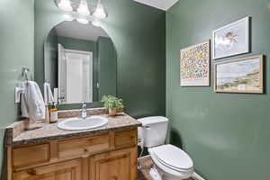 Half bath with a textured wall, vanity, toilet, and tile patterned floors