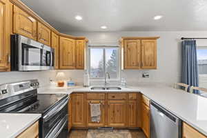 Kitchen featuring light countertops, appliances with stainless steel finishes, a sink, and recessed lighting