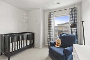 Bedroom featuring carpet, visible vents, a crib, and baseboards