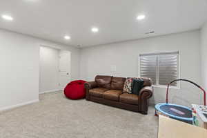 Living room with baseboards, visible vents, light colored carpet, and recessed lighting