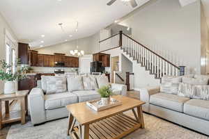 Living room featuring recessed lighting, baseboards, high vaulted ceiling, ceiling fan with notable chandelier, and stairs