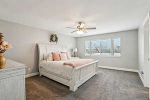 Bedroom with baseboards, dark carpet, and ceiling fan