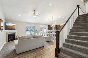 Living room featuring stairs, lofted ceiling, recessed lighting, light wood-type flooring, and a glass covered fireplace