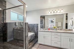 Bathroom featuring a garden tub, a sink, a shower stall, and double vanity