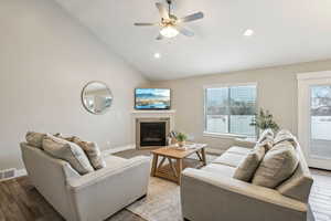 Living room with light wood-style flooring, baseboards, a glass covered fireplace, and visible vents