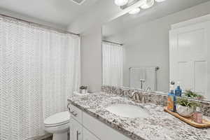 Bathroom with a shower with shower curtain, vanity, and toilet